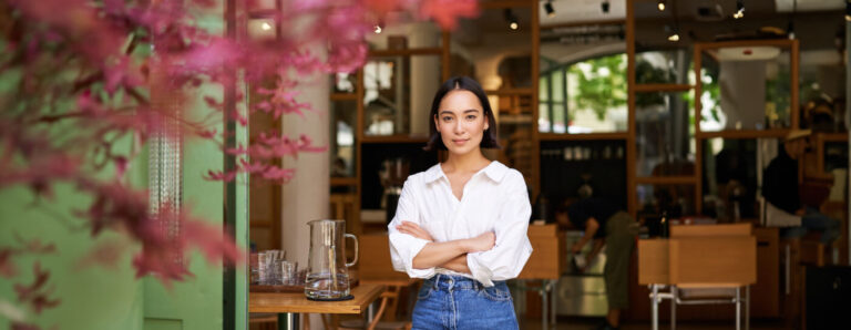 Young businesswoman standing at the entrance of her own cafe