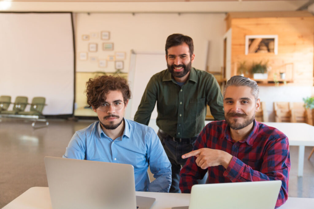 Happy startup team with laptops celebrating in a boardroom